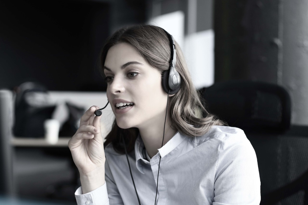 Beautiful smiling call center worker in headphones is working at modern office.